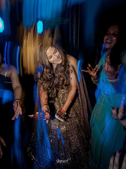 The bride dances with joy, captured with a slow-shutter effect to show the energy and excitement of the engagement party.