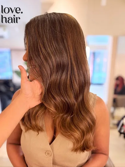 This image shows how different lighting can completely change the look of a hair color. Here, the bronde balayage appears softer and more blended in indoor light.