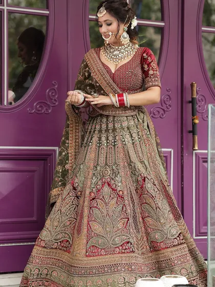 A full shot of a heavily embroidered bridal lehenga in shades of maroon and olive green. This is a unique color combination for the bride who wants to stand out.