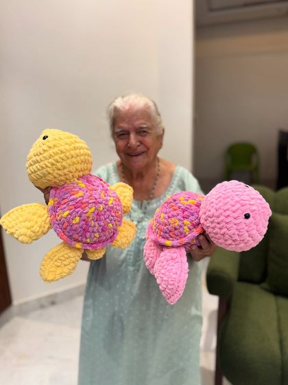 Dadi with two of her colorful sea turtle creations. These plush toys are made with thick, soft yarn, making them incredibly squishy and huggable.