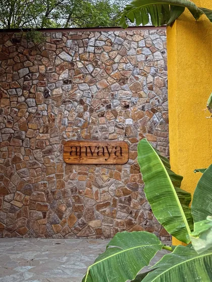 The Anvaya sign, carved in wood and set against a rustic stone wall, marks the entrance to your quiet escape.
