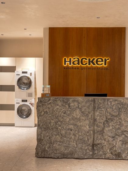 The reception of our newly revamped Delhi showroom and India Headquarters, featuring a desk with a raw stone front and our illuminated logo on a wood-paneled wall.