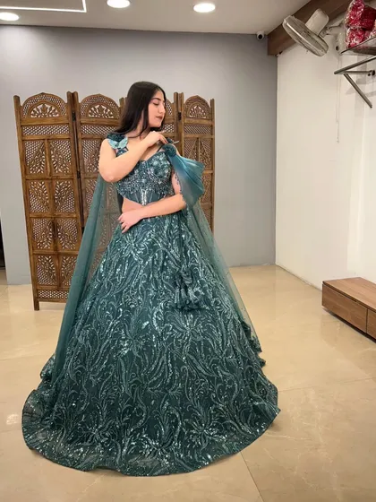 The full view of this magnificent teal sequin gown. The dramatic flare and unique shoulder detail make it a showstopper.