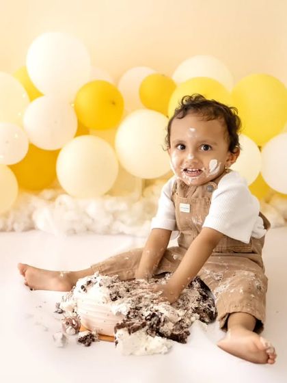 A super cute shot of the baby looking at the camera with a frosting-covered face and hands.