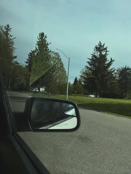 An aesthetic shot from a car window, capturing a view of the road and trees.