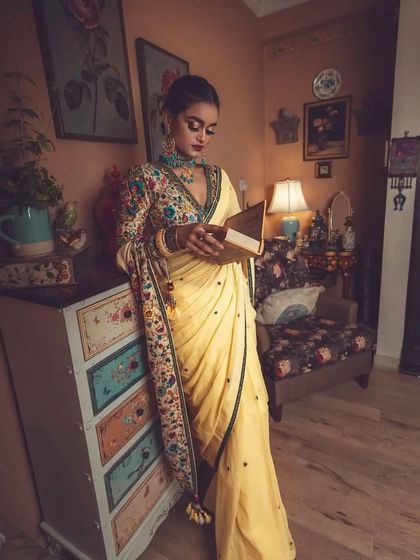 Creating a story through styling. In this shot, the model, dressed in the elegant yellow saree and embroidered blouse, interacts with the vintage-inspired set, adding a narrative quality to the fashion photograph.