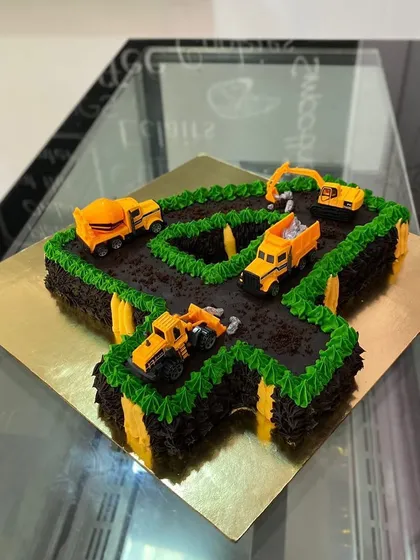 A number-shaped cake for a 4th birthday. This construction-themed "4" is made of chocolate cake "dirt" and decorated with toy trucks.