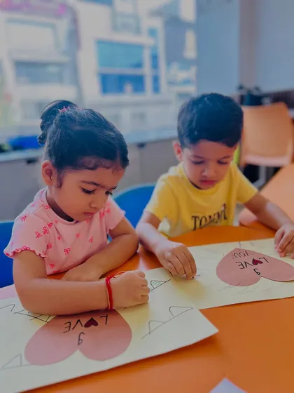 Two children work side-by-side on their heart-themed crafts. This shows how our activities encourage parallel play and shared creative experiences.