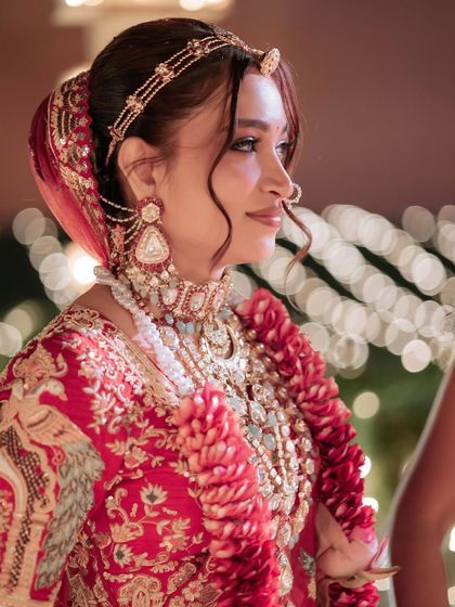 A side profile showcasing the bride's elegant makeup and hairstyle. The soft tendrils framing her face add a touch of romance to the look.
