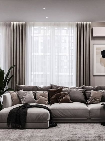 A cozy and minimalist living room setup. The plush grey sectional sofa is perfect for relaxing, while the large plant and simple artwork add a touch of nature and personality.