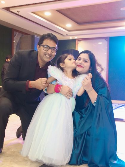 A daughter gives her mom a kiss on the cheek while her dad joins in for a happy family photo.