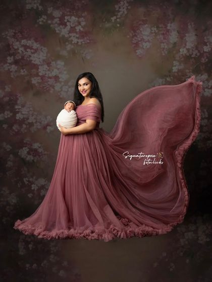 A mother's embrace. This stunning portrait captures a new mother holding her baby, with the flowing gown creating a sense of ethereal beauty and grace.