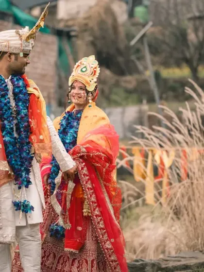 The couple shares a happy, candid moment after their wedding rituals at the sacred temple in Uttarakhand. Their traditional attire looks stunning against the rustic, natural setting.