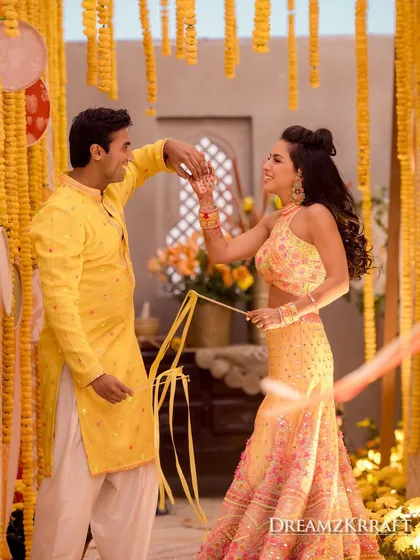 A candid dance moment during a vibrant Haldi ceremony. The decor, with its bright marigold garlands, creates a festive and traditional backdrop for these joyful celebrations.