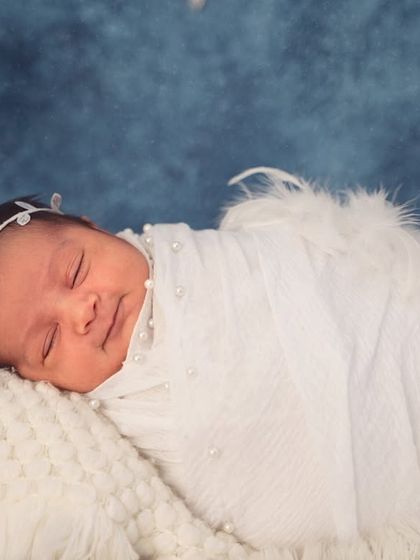 The soft lighting and angelic theme create a heavenly mood for this portrait of a sleeping newborn with delicate feather wings.
