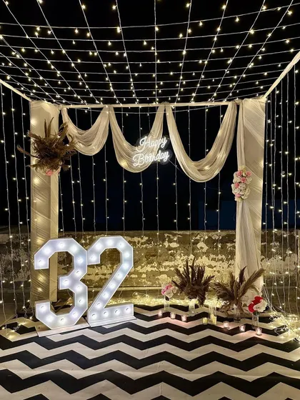 We transformed this rooftop into a magical space for a 32nd birthday celebration. A canopy of fairy lights, elegant white drapes, large marquee numbers, and a stylish chevron floor created an intimate and sophisticated ambiance for the special night.