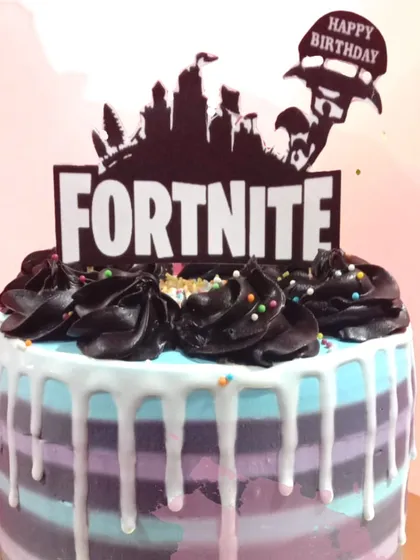 A victory royale for a Fortnite fan's birthday. This cake captures the game's aesthetic with its purple and blue stripes, white chocolate drip, and iconic logo topper, making it the perfect fuel for a gaming party.