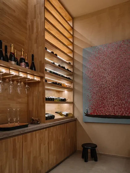 We designed this custom wine cellar with warm wood and integrated lighting to create an intimate and inviting space for the client's collection. The artwork adds a splash of color and personality.