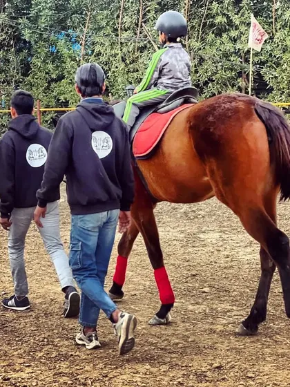 Our staff, easily identifiable in their club hoodies, ensure every rider is safe. Here, two trainers escort a young rider during his session.