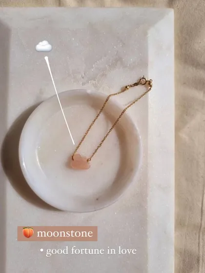 A healing charm bracelet featuring a peach moonstone cloud. This stone is known for bringing peace, calm, and good fortune in love.