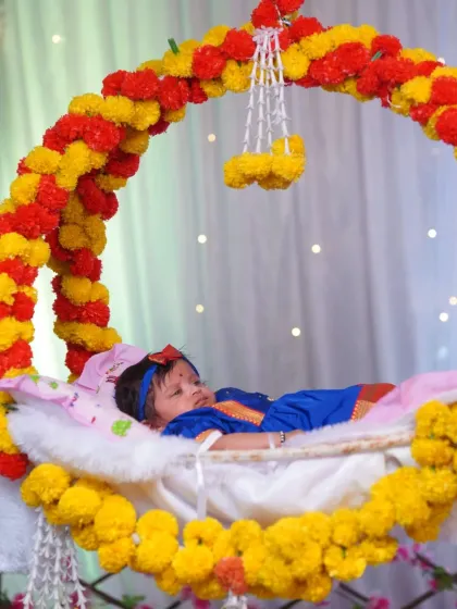 A traditional Marathi naming ceremony, or 'barsa'. This shot captures the baby peacefully resting in a beautifully decorated floral cradle, a key moment of the ceremony.