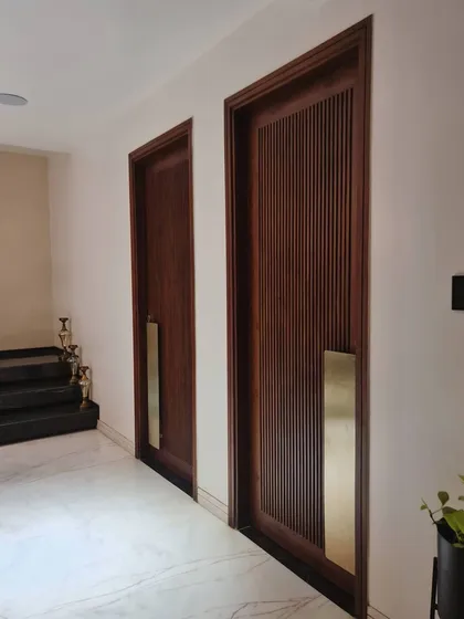 Detail is paramount in our work, as seen in these custom-designed teak wood doors with integrated brass handles. The fluted texture of the wood combined with the smooth, metallic pull creates a tactile experience that signals the luxury and craftsmanship within.