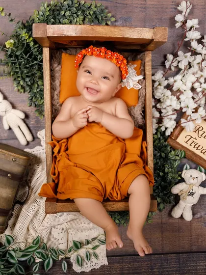 A full-body shot of a happy baby girl in a rustic wooden bed prop, personalized with her name. She was so expressive during her session.