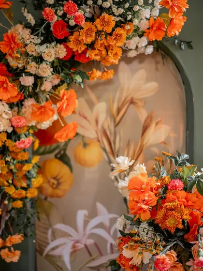 A close-up of a welcome decor setup at a Goa resort, with a vibrant orange floral arrangement against a painted archway.