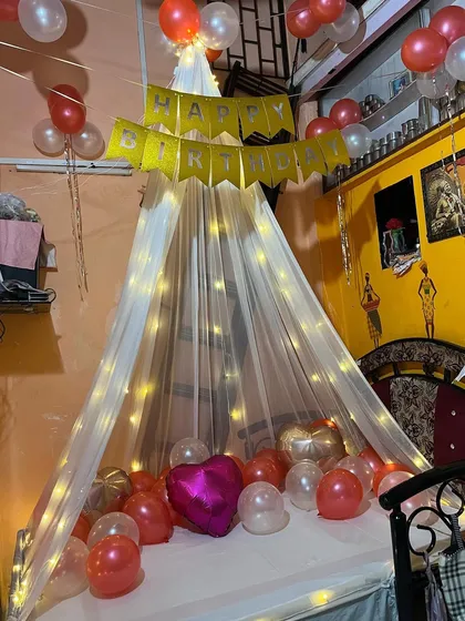 A full view of the birthday canopy setup, showing the "Happy Birthday" banner and balloons floating around the room.