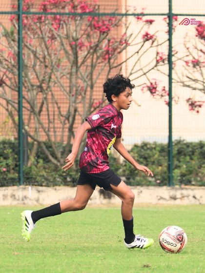 A young player runs with the ball against a beautiful backdrop, fully absorbed in the game.