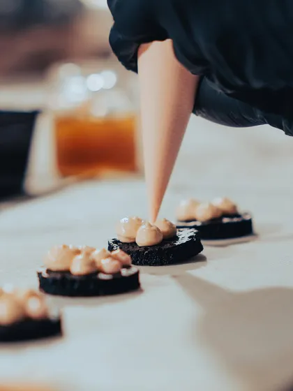 A close-up of our team piping a delicate topping onto small appetizers for the Versailles-themed dinner. This shot highlights the precision and care that goes into every single bite.