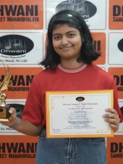 A student proudly holds her certificate and trophy.