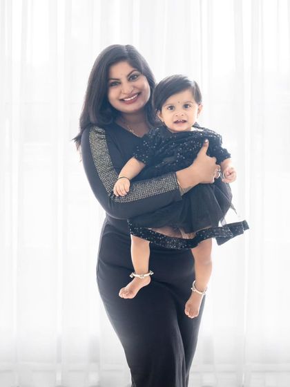 A mother and daughter in stylish matching black outfits, smiling for the camera.