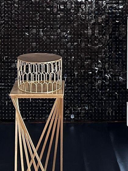 A modern gold cake stand on a twisted pedestal, set against a black shimmer wall. This highlights the high-quality props I use to complement my decorations.