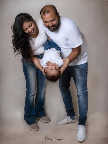 A playful family photo where the parents are holding their laughing baby upside down, capturing a moment of pure fun and connection.