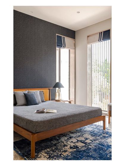 A bedroom in the 'Solid Void Solid' house, where a dark, textured accent wall contrasts with the light-filled room. The design balances bold statements with calm, neutral tones to create a sophisticated and restful private space.