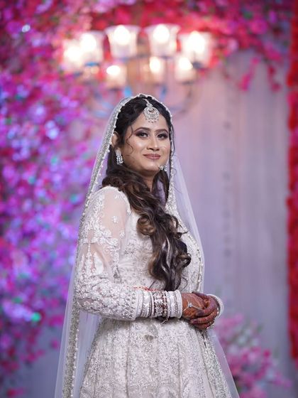 A beautiful portrait of a bride in her white wedding gown, set against a vibrant pink floral background. Her happy and confident smile says it all.