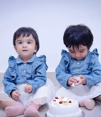 One twin looks at the camera while the other investigates the cake. Capturing the unique personalities of siblings is one of our favorite things to do.