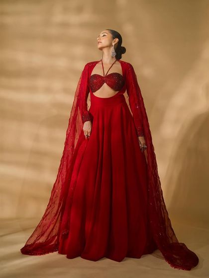 An ethereal shot from the 'Scarlet Edit', with the model looking upwards in a red gown with a sheer, flowing cape.