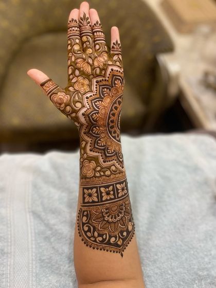 A beautiful, finished design on the back of the hand and arm, showcasing a mix of floral and mandala elements.