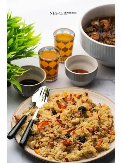 A plate of Bengali-style fried rice served with a side of chili fish. This bright, clean shot highlights the colors and textures of this popular Indo-Chinese meal.