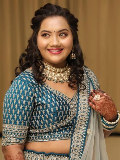 A close-up of a happy client wearing an elegant choker necklace that perfectly matches her teal lehenga.