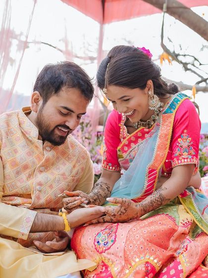 A candid moment of the couple laughing as the groom playfully examines the bride's henna design.