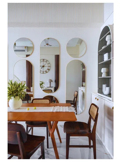This dining space in 'Apartment 601' is designed for modern living. The extendable table and multi-functional crockery unit are perfect for hosting, while the mirrors are a Vastu-compliant touch.