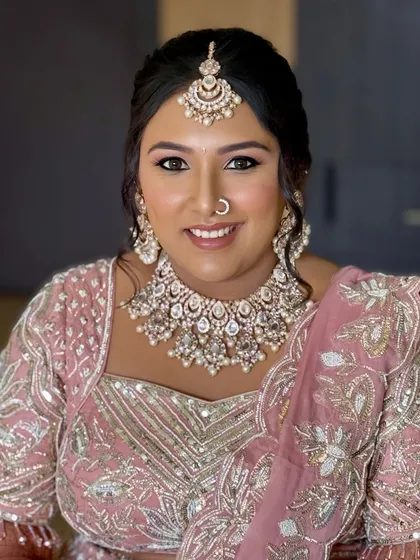 A happy, smiling portrait of the bride. The makeup is fresh and youthful, perfect for her pastel pink lehenga.