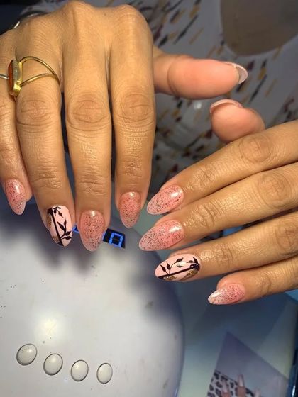 A pretty design with a pink glitter base and black bamboo-like silhouettes on the accent nails.