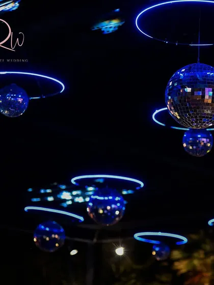 A ceiling of disco balls and blue neon rings, designed for a high-energy after-party. This lighting creates a fun, club-like atmosphere.