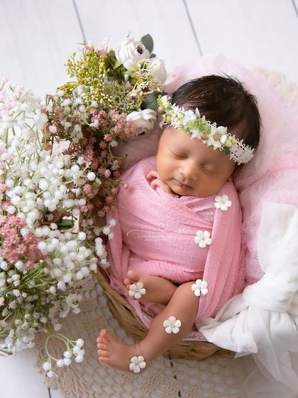 Another beautiful floral setup, with the baby nestled in a basket overflowing with pink and white baby's breath. It's a classic and delicate look.