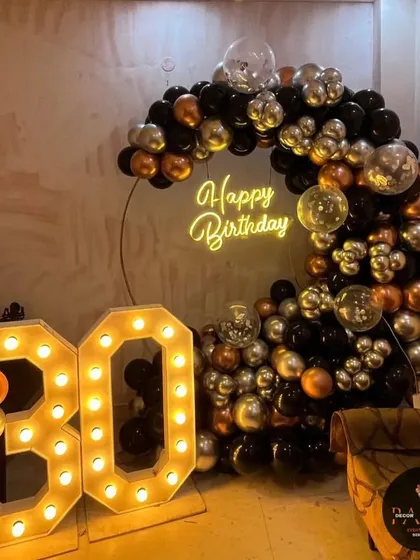 A modern and stylish balloon arrangement for a 30th birthday, using black, silver, and bronze chrome balloons with large marquee numbers.