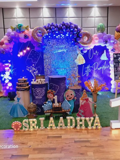 The complete setup for the Cocomelon and ice cream party, with marquee letters spelling out the name "Sri Aadhya" on a turf floor.